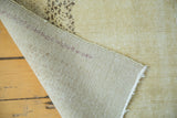 Distressed Oushak rug showing hand-knotted foundation and worn lemon ivory pile.