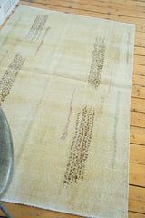 Distressed Oushak rug with abstract brown motifs and faint colorful lines on lemon ivory pile.