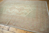 Angled view of vintage Oushak carpet with pastel medallion and intricate layered borders.
