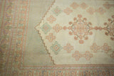 Vintage Oushak carpet detail: pastel peach, green, and lavender geometric motifs on a cream field.