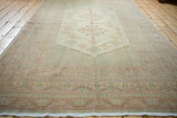 Vintage Oushak carpet border detail showcasing pastel stylized motifs and soft fringe.