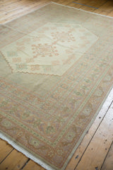 Intricate corner of a vintage Oushak rug, with pastel green, peach, and soft purple borders.