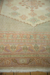 Pastel orange, green, and lavender stylized bird motifs in a vintage Oushak rug border.
