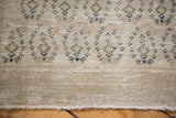Oushak rug edge with textured slate beige pile, blue geometric motifs, and short fringe.