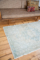Bottom edge detail of a Vintage Oushak rug, showing blanched ivory and faint powder blue hues.