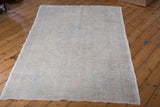 Distressed Oushak rug edge with blanched texture and faded pastel patterns.