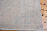 Distressed Oushak rug's blanched tones, faded motifs, and low pile texture at the edge.