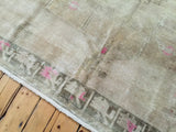 High sheen pile of the vintage Oushak rug showing geometric beige, soft bronze, pink motifs.