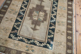 Vintage Oushak rug corner with a geometric dark blue border and muted earth-tone medallion.