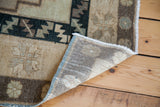 Vintage Oushak rug corner showing hand-knotted foundation and geometric pattern in neutral tones.