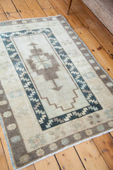 Fringed corner of the Oushak rug, displaying geometric borders and light beige field.
