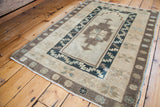 Geometric motifs and patterned borders on a vintage Oushak rug in beige, brown, and teal.