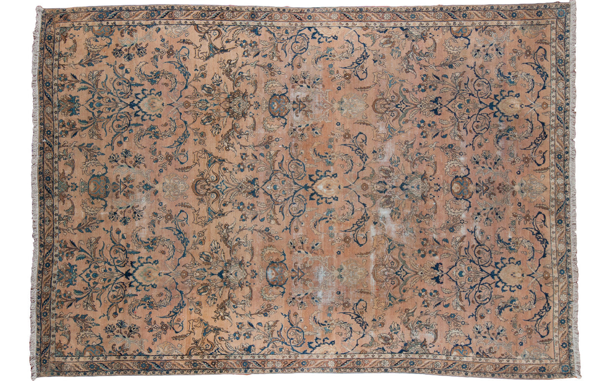 Distressed antique Persian Kerman carpet with sprawling palmettes and samovar motifs in faded peach and blue.