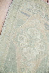 Soft hand-knotted wool pile in subtle green, beige, and gray geometric pattern with abrash.