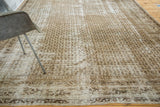 Distressed Persian carpet displaying faded ivory and charcoal boteh pattern with visible texture.