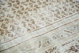 Textured detail of distressed vintage Persian carpet with faded ivory and charcoal boteh.