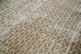 Faded ivory and dark charcoal boteh pattern on textured pile of distressed Persian carpet.