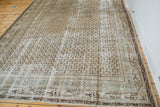 Distressed Persian Serbend carpet corner, highlighting faded ivory, charcoal, and repeating boteh field.
