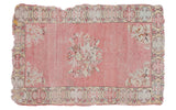 Distressed 3x5 Oushak rug with faded rose pink, central floral bouquet, and overcast edges.
