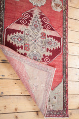 Vintage Oushak runner's folded corner, revealing hand-knotted foundation and cranberry red field.