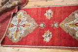 Hand-knotted Oushak runner displaying cherry red field, bronze medallion, and ivory florals.