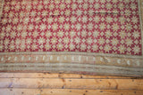 Repeating geometric starburst pattern in cranberry red and beige on a vintage Oushak rug.