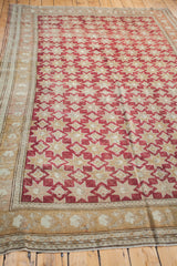 Vintage Oushak carpet's geometric star field in cranberry wine-red and bronze ivory.