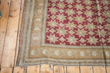 Vintage Oushak rug corner with cranberry geometric stars and bronze-ivory border motifs.