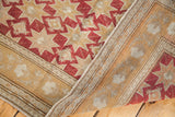 Folded corner of vintage Oushak rug, showcasing cranberry red geometric pattern and hand-knotted weave.