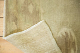 Folded corner of Vintage Turkish Oushak rug, showing earth tone pile, subtle charcoal patterns, fringe, and woven back.