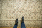 Distressed Oushak rug's pale ivory field, earth-tone allover pattern, and border underfoot.