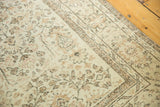 Distressed pile texture of an Oushak rug, showing pale ivory field and earth-tone motifs.