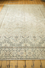 Distressed allover design on pale ivory field and earth-tone outlines of vintage Oushak rug.