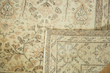 Distressed ivory Turkish Oushak pile with earth-tone design, revealing hand-knotted foundation.