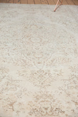 Faded, blanched ivory Oushak rug with subtle peach and mint green floral motifs.