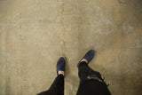 Distressed Oushak carpet showing its soft beige and faded slate green texture underfoot.