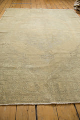 Soft beige and slate green distressed Oushak carpet with faded pattern.