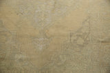 Distressed Oushak carpet texture showing low pile, soft beige, and faint slate green.