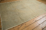 Geometric pattern detail of the distressed Oushak carpet in soft beige and slate green.