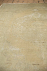 Textured, distressed surface of the Oushak carpet in soft beige and slate green.