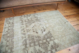 Distressed Oushak rug showing soft brown patterns fading into a light tone-on-tone field.