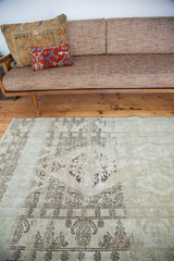 Low pile texture and soft ivory with faded brown tone-on-tone pattern on distressed Oushak rug.