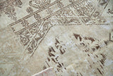 Worn texture of distressed Oushak rug; faded brown patterns on light beige pile.