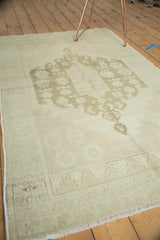 Hand knotted Oushak rug corner, showcasing its geometric beige border and fringe.