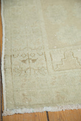 Oushak rug corner showing subtle geometric pattern, tone-on-tone ivory pile, and fringe.