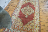 Vintage Oushak rug with deep cinnabar red field, ivory, and orange floral patterns.