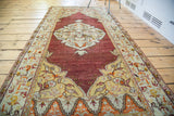 Vintage Turkish Oushak runner with deep cinnabar red field, ivory medallion, and orange floral motifs, 3'3