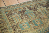 Distressed Belouch runner showing geometric patterns and architectural motifs in soft green and charcoal brown.