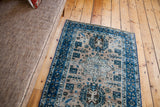 Distressed Heriz rug with ivory field, deep blue borders, and geometric patterns.