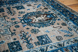 Distressed Heriz rug detail: textured pile, meandering blue and brown geometric motifs on ivory.